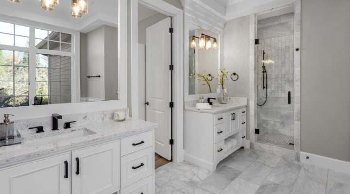 An elegant marble-tiled bathroom with warm pendant lights on the vanity area