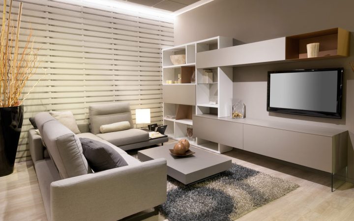 A living room with elegantly designed interior, a contemporary shelves, a sofa set, center table, table rug, corner ornament, lamp, a wall-mounted flat screen