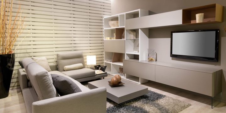 A living room with elegantly designed interior, a contemporary shelves, a sofa set, center table, table rug, corner ornament, lamp, a wall-mounted flat screen