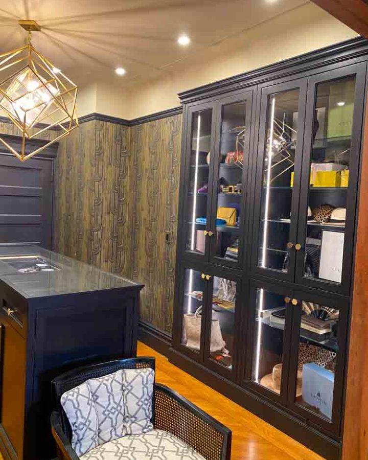 A walk-in closet with installed cabinets for bags and accessories; cabinet doors are glass for elegant display of bags