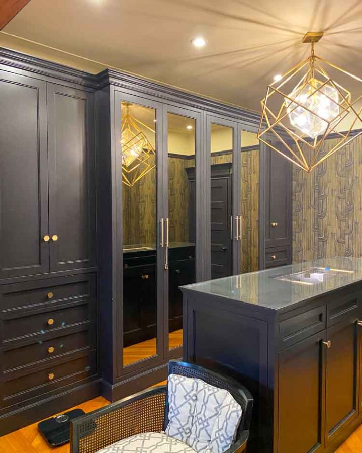 A walk-in closet with installed cabinets for organized clothes; cabinet doors have mirror for space maximization