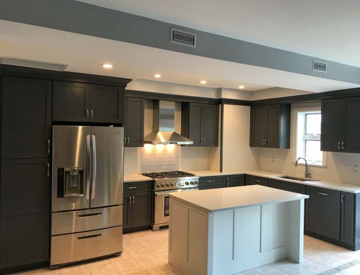 A sleek monochrome kitchen with dark colored cabinets, a stove range, an exhaust hood with warm lights, and a double door refrigerator